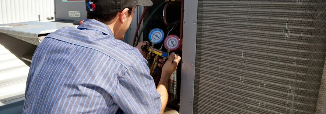 HVAC technician servicing a condenser unit in Hillside